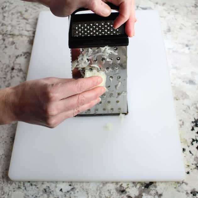 Grating onion onto white cutting board