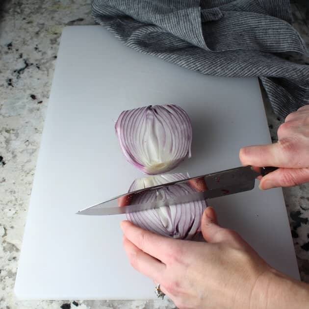 Cutting red onion on a cutting board.