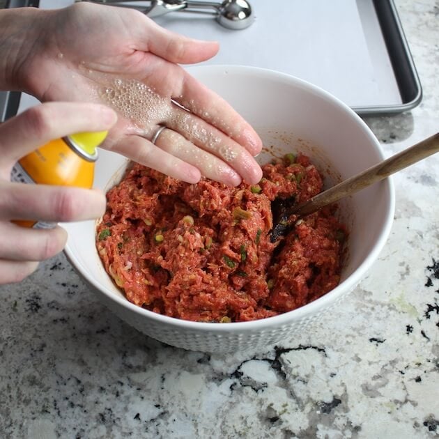 Spraying hands in preparation to roll the asian meatballs.