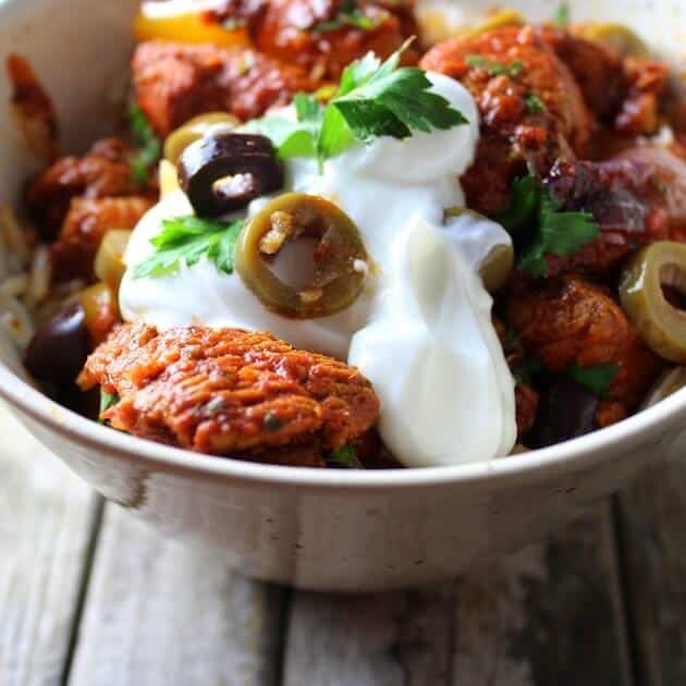 Partial bowl closeup of spicy chicken with sour cream and olives