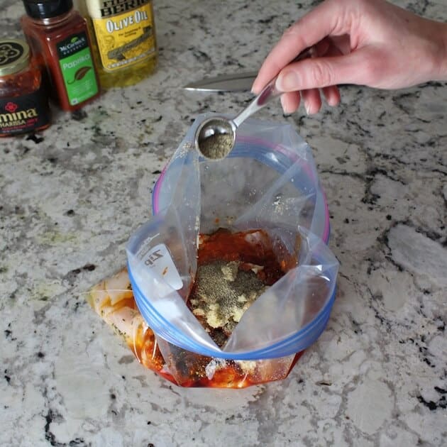 Adding pepper to ziploc to marinate harissa chicken