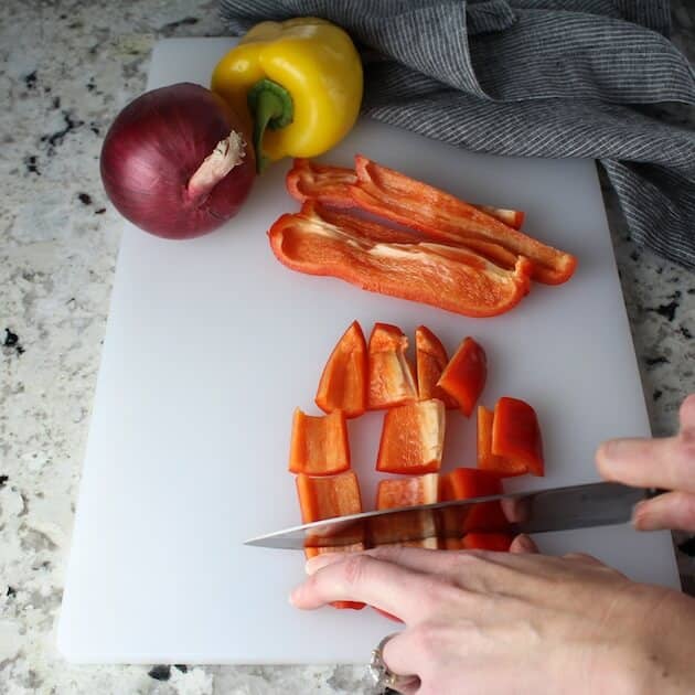 Cutting red peppers on a cutting board.