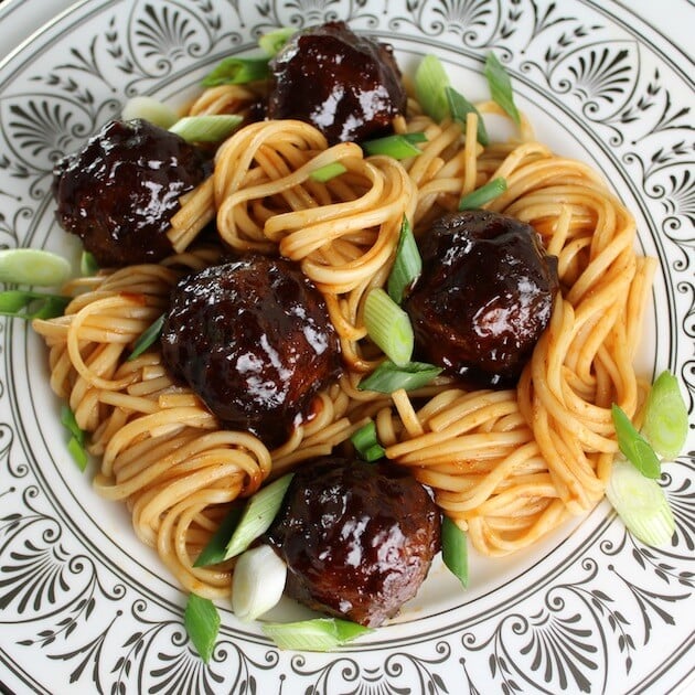 Asian Meatballs on decorative plate with noodles and chopped green onions