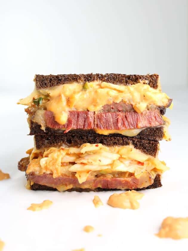 closeup of tall stacked reuben sandwich on white table with white background