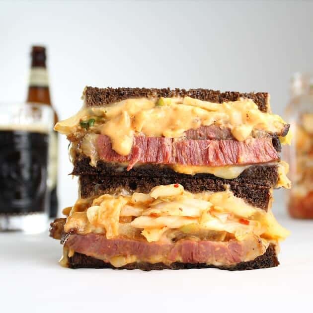 A grilled Reuben Sandwich with beer in the background.