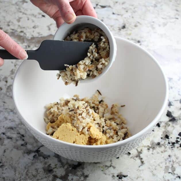 Adding rice to mixing bowl for vegetarian meatballs