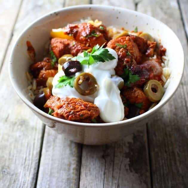 Bowl of spicy chicken topped with yogurt and olives