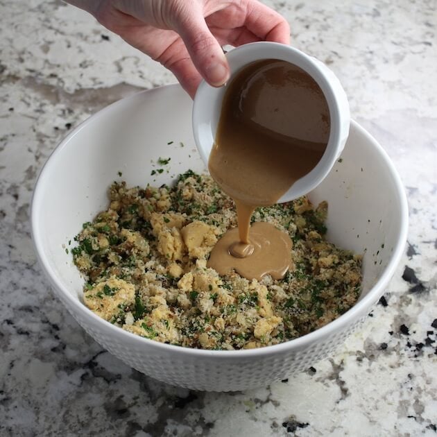 Adding tahini to mixing bowl of ingredients