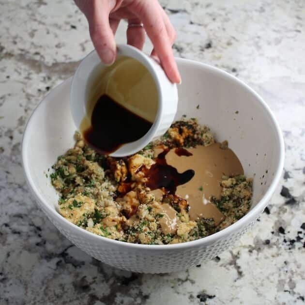 Adding tamari to a mixing bowl of ingredients 