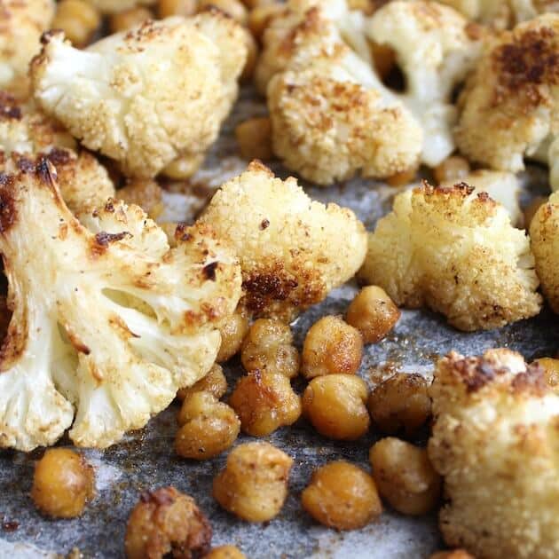 Close up Roasted Cauliflower And Chickpeas on baking sheet with parchment paper 