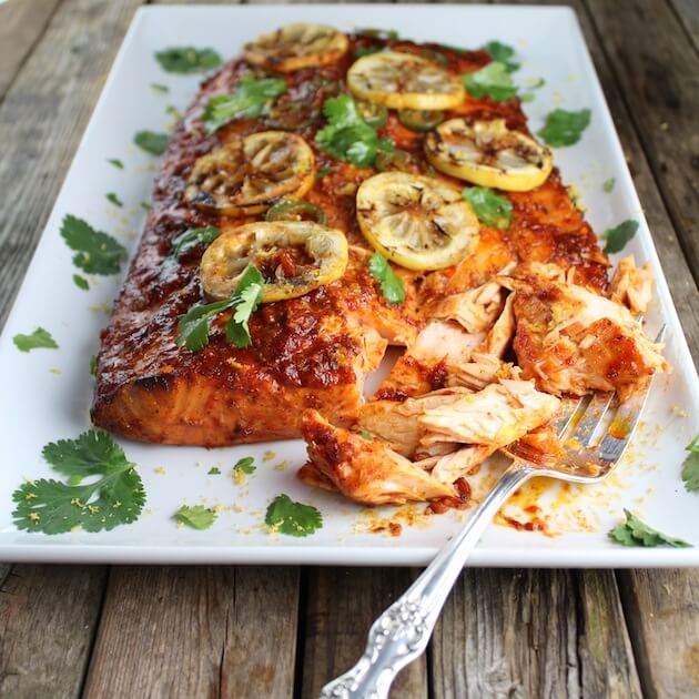 Platter of Cedar Plank Harissa Smoked Salmon with lemon garnish