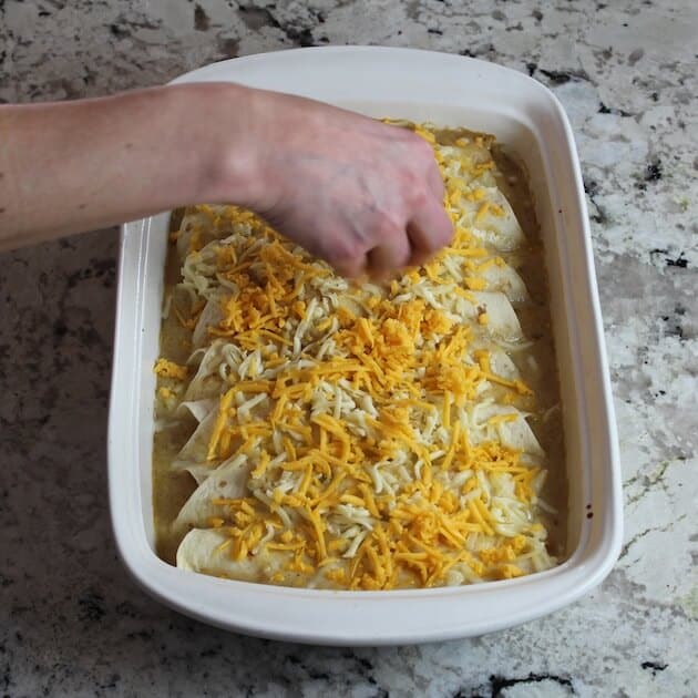 Adding shredded cheddar on top of enchiladas