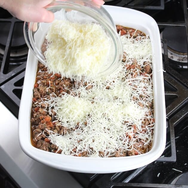 Sprinkling shredded cheese on top of lasagna