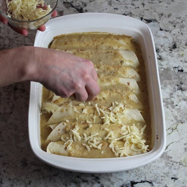 Adding shredded cheese on top of enchiladas