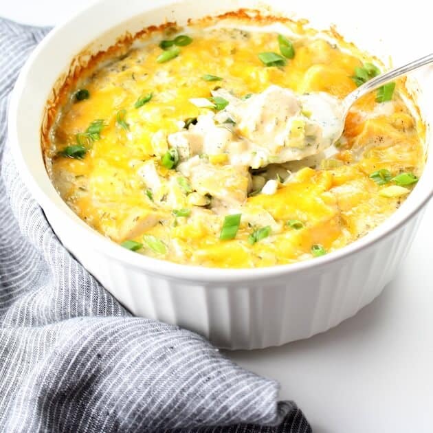 Spatula scooping Cheesy Hot Chicken Salad out of baking dish