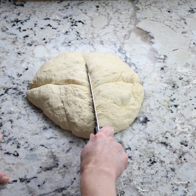 cutting pizza dough into quarters 