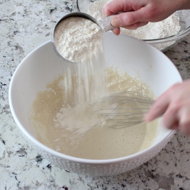 Adding flour to pizza dough batter in mixing bowl