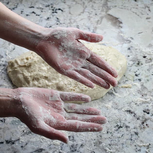 floured hands ready to roll pizza dough