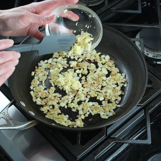 adding garlic to saute pan with cooked onions