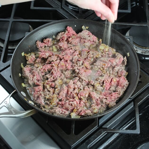 Adding salt to ground lamb cooking in saucepan