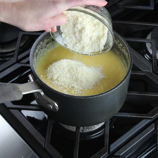 Adding parmesan cheese to polenta while cooking in saucepan