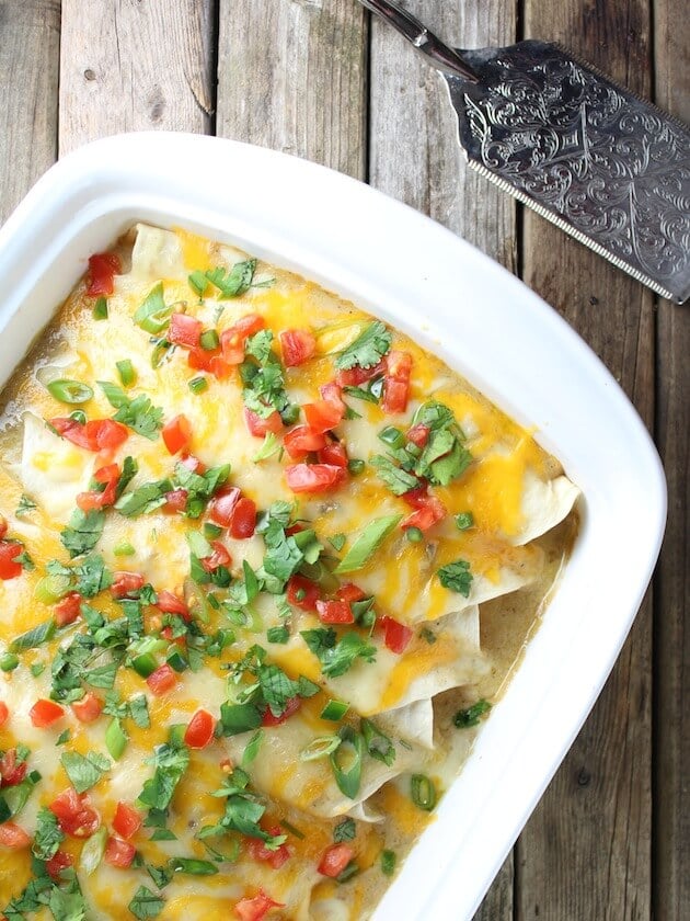 Cheesy Chicken Enchiladas in Casserole dish with decorative antique spatula