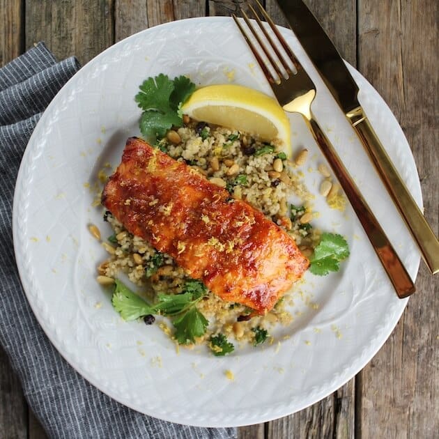 Dinner plate with smoked salmon filet on couscous, with napkin and gold silverware 