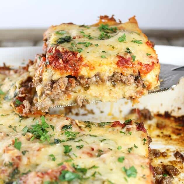 Spatula holding a piece of Lamb Lasagna With Parmesan Polenta above baking dish