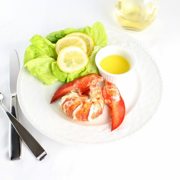 lobster meat out of the shell on a plate with silverware and glass of wine