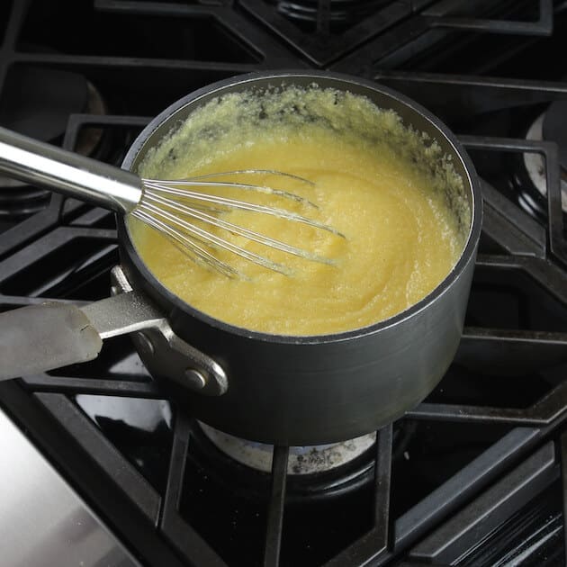 Pot of cooked instant polenta with wire whisk