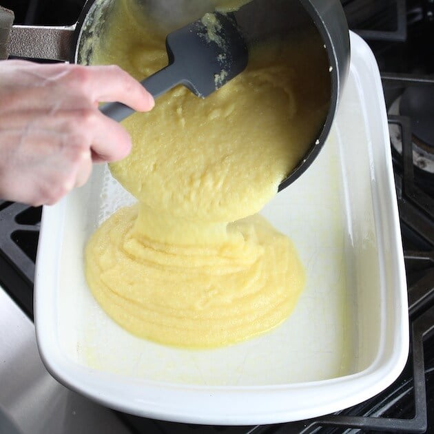 pouring polenta into bottom of casserole dish for lasagna