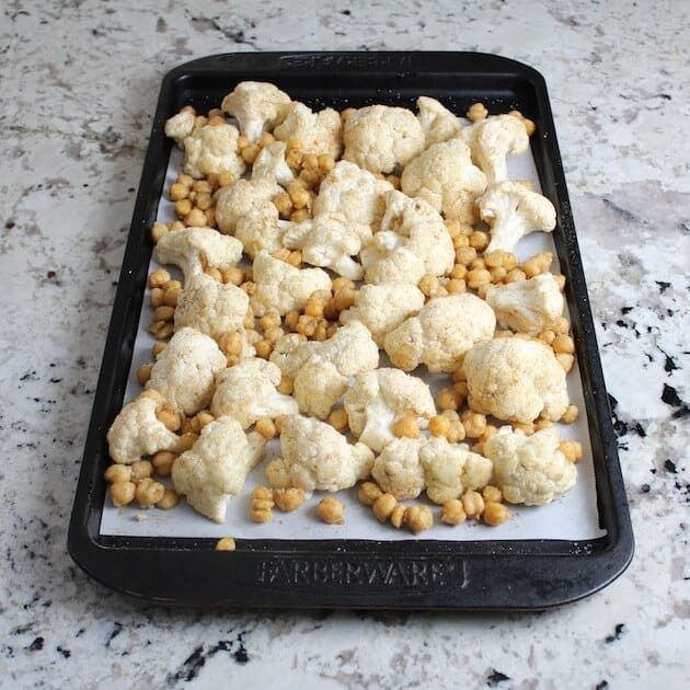 Florets of cauliflower &amp; chickpeas on baking sheet ready for oven