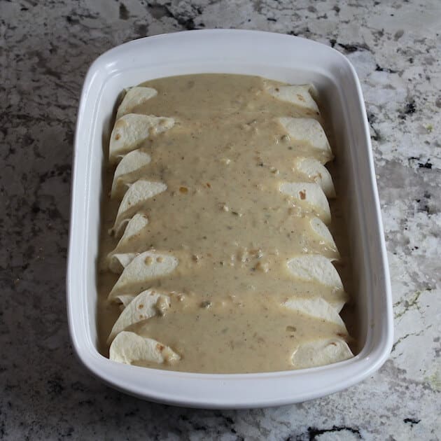 Chicken Enchiladas in dish covered in sauce and ready for the oven