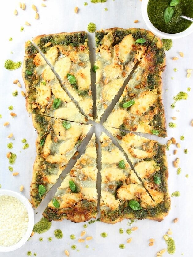 Whole rectangular chicken pesto pizza sliced into wedges