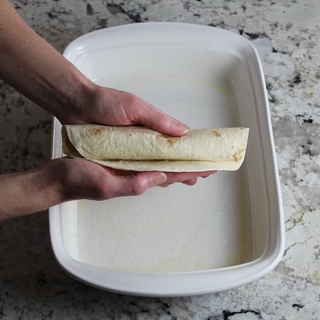 Rolling up chicken stuffed tortilla for enchiladas