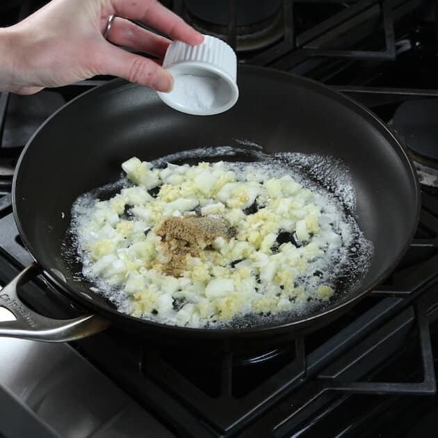 Adding salt to saute pan with onions and garlic