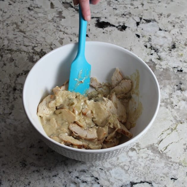 stirring together chicken and cheesy enchilada sauce in mixing bowl