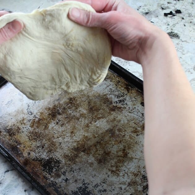 Working pizza dough out for cooking sheet