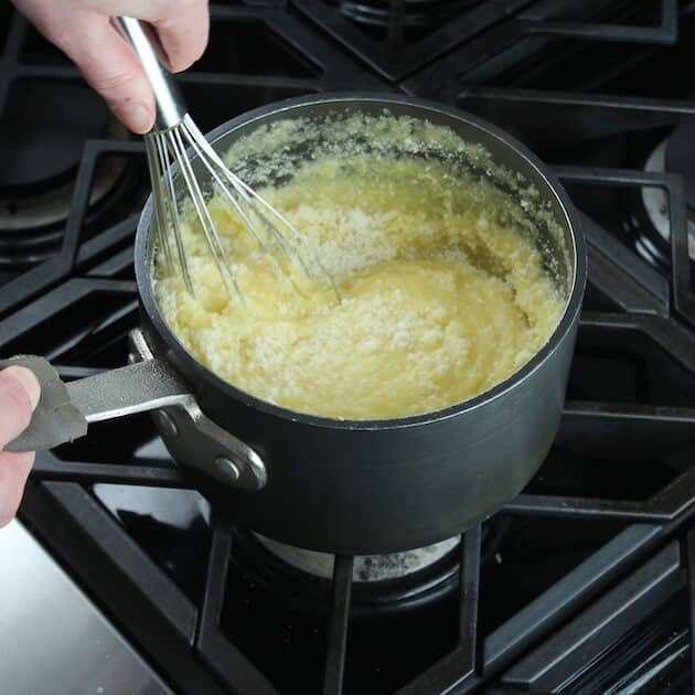 Whisking parmesan into polenta while cooking 