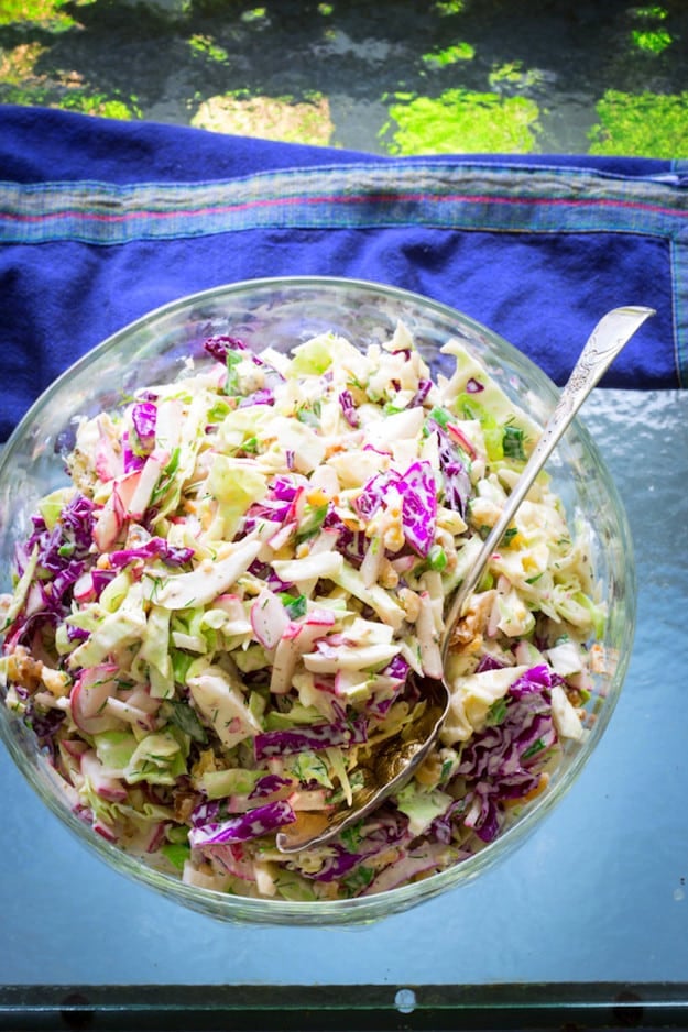 coleslaw with walnuts in glass bowl on blue tablecloth