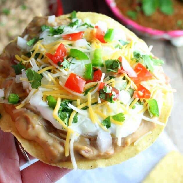 Hand holding Mexican pizza with refried beans and toppings 