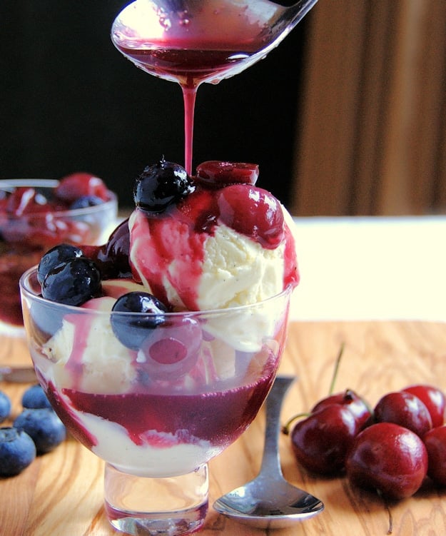 Cherry sauce pouring over a glass of vanilla ice cream