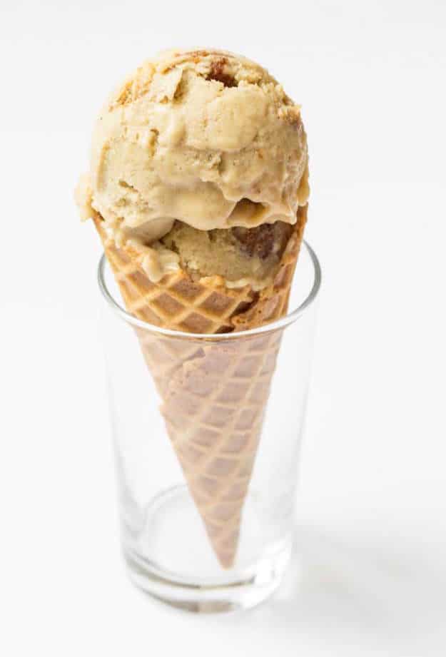 Beige scoop of ice cream on a sugar cone sitting in a small drinking glass