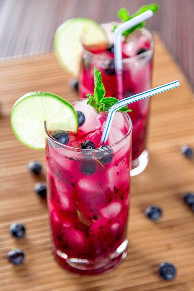 Tall glasses with purple drink and lime garnish 