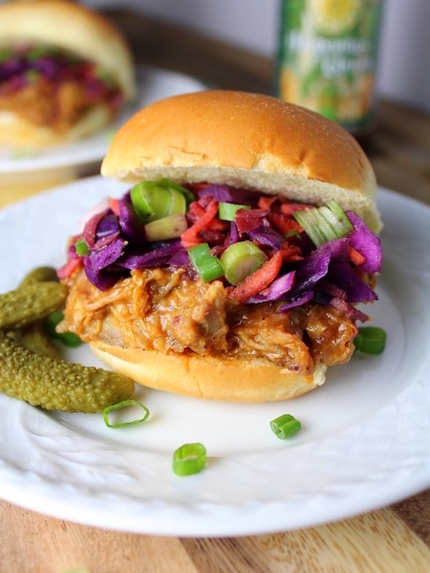 Pulled pork slider sandwich on white side plate with pickles