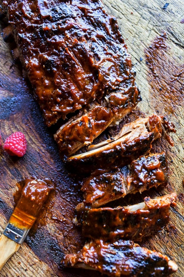 Rack of baby back ribs on cutting board with sauce