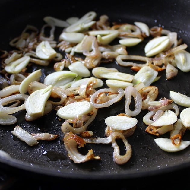 Sliced garlic and onions cooking in saute pan