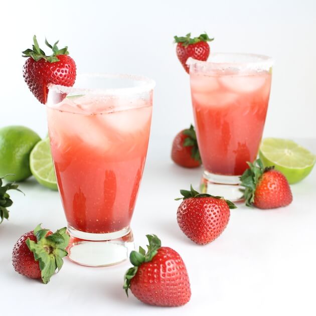Two Fresh Strawberry Margaritas with strawberries and limes