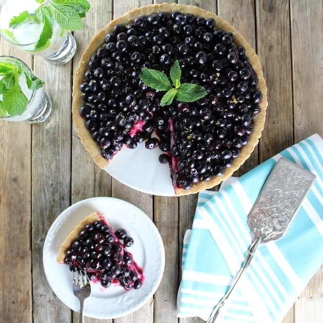 Blueberry Tart with slice cut out on a serving plate
