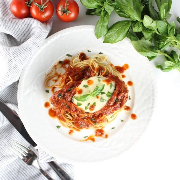 Chicken Caprese on dinner plate with fresh basil and tomatoes